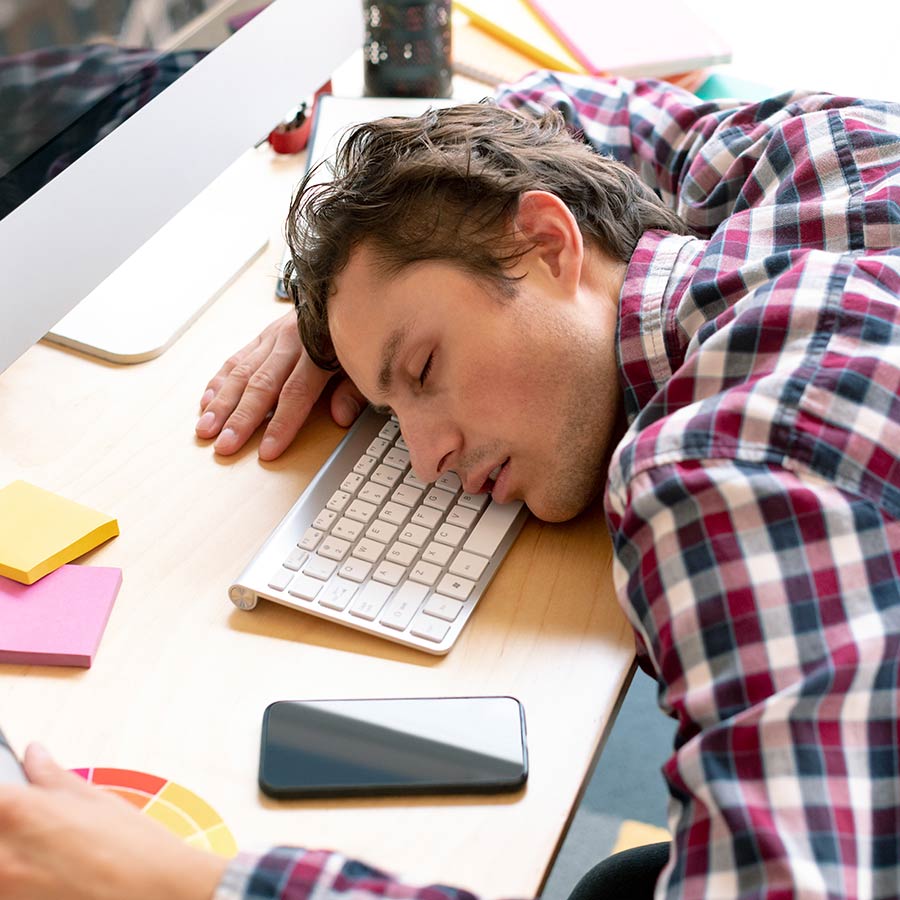 Ein Mann ist vor innerlicher Erschöpfung am Arbeitsplatz eingeschlafen.